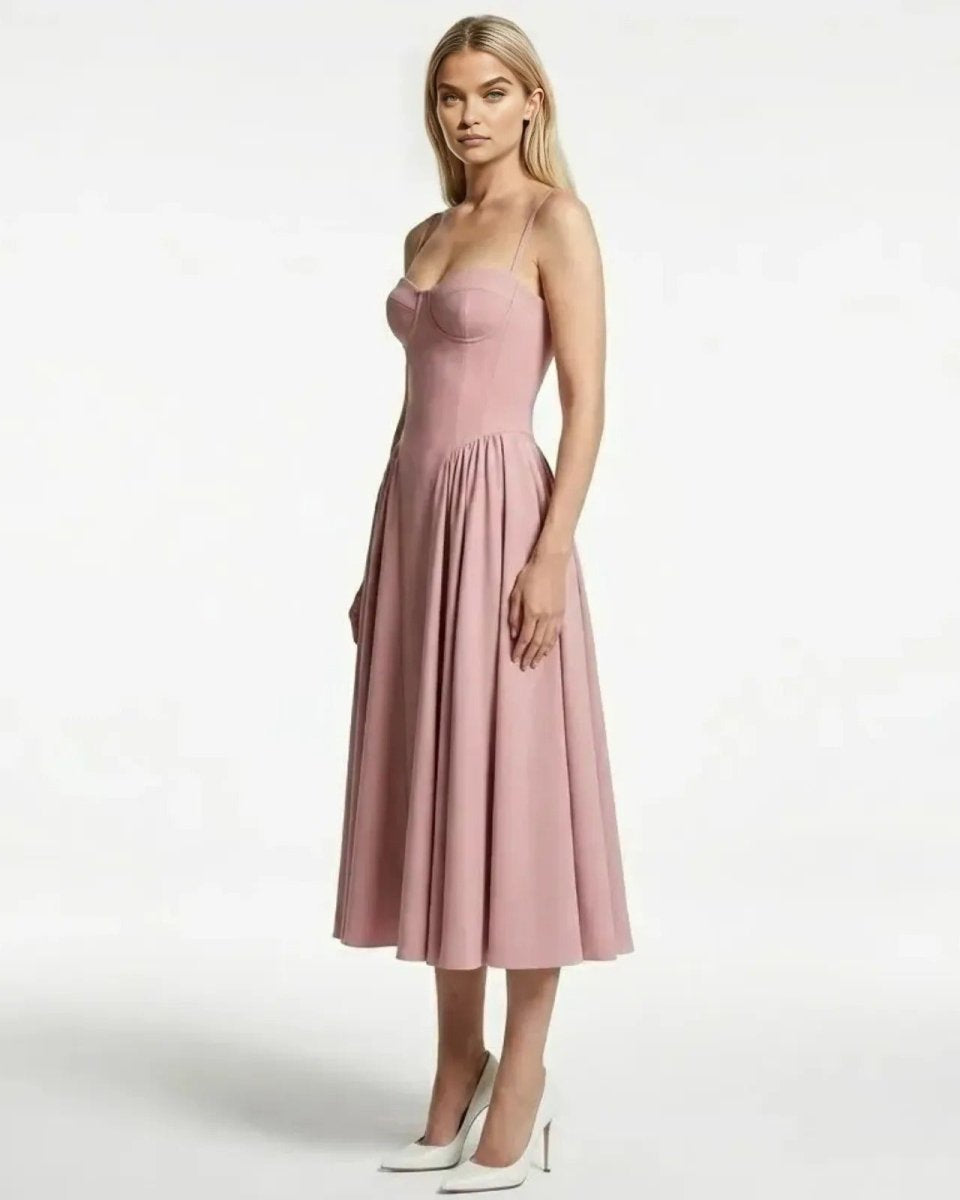 Side profile of a model in the Evdokia pink cocktail dress, showing the fit of the bodice and the volume of the pleated midi skirt.
