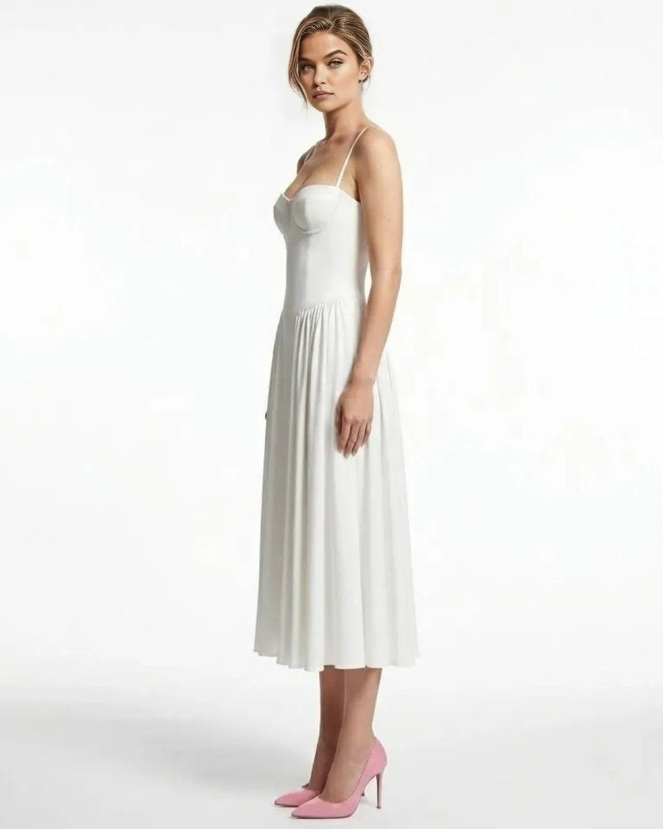 Side profile of a model in the Evdokia white midi dress showing the structured bodice and pleated A-line skirt.