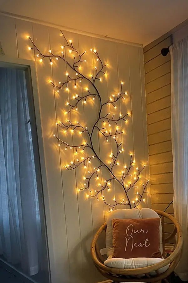 Decorative wall with illuminated branches and a chair with a 'Our Nest' pillow.