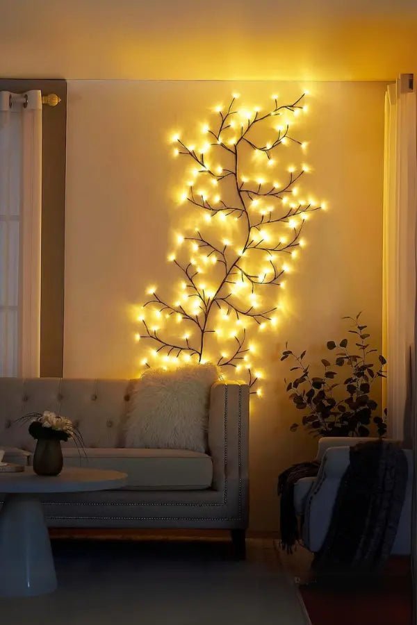 Decorative wall light fixture with glowing branches in a living room setting.