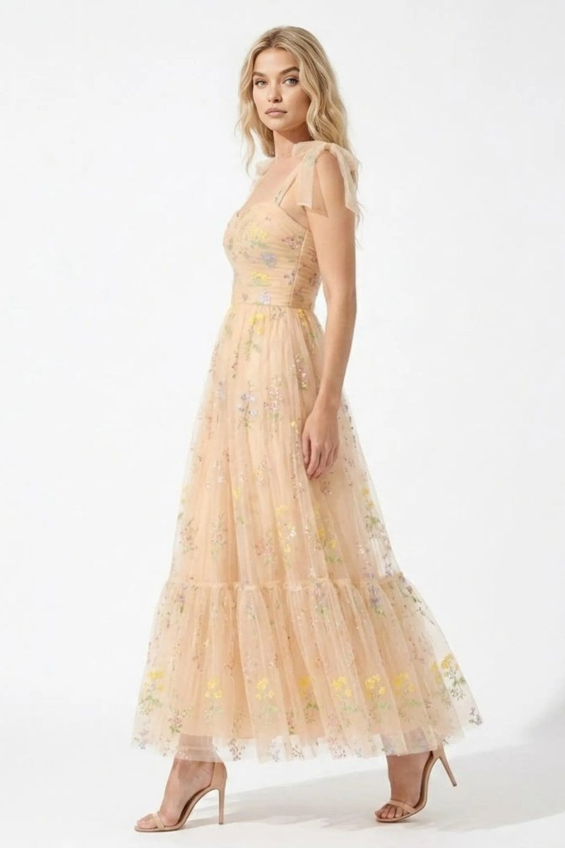 Side profile of elegant tiered tulle maxi dress with champagne floral embroidery and fitted bodice.