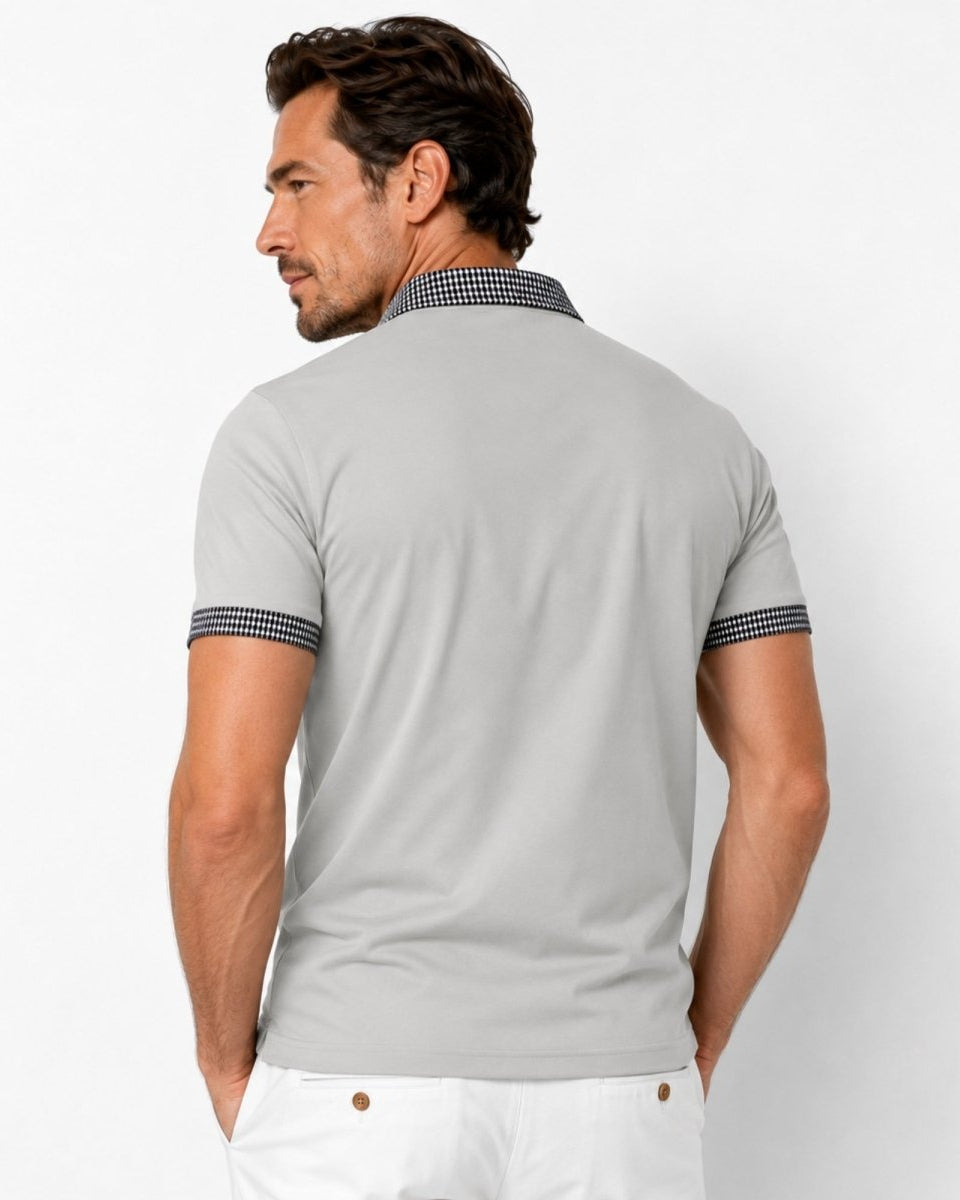 Man wearing a light gray polo shirt with a checkered collar on a white background