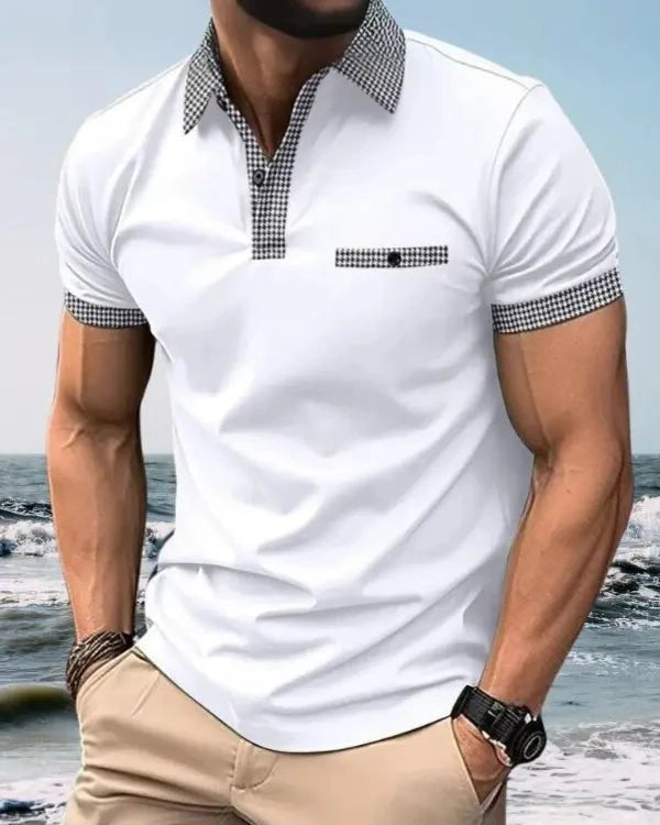Man wearing a white polo shirt with checkered collar and cuffs on a beach.