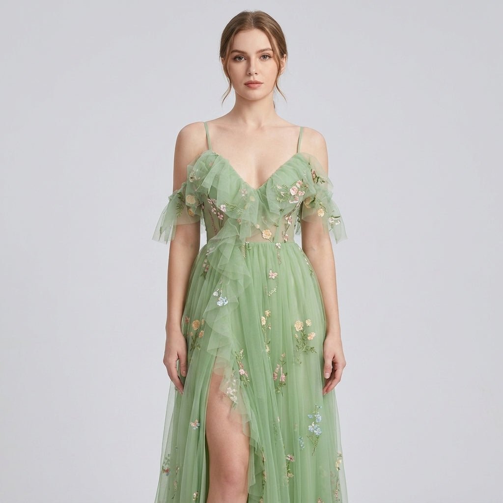 Close-up front detail of green fairycore gown showcasing intricate pink and yellow floral embroidery, corset boning, and off-shoulder ruffle sleeves.