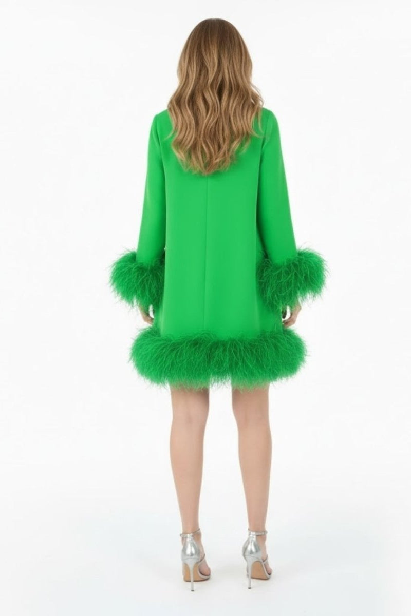 Back view of a model wearing the Kouvr green feather mini dress, showing the dress's structure and long sleeves.