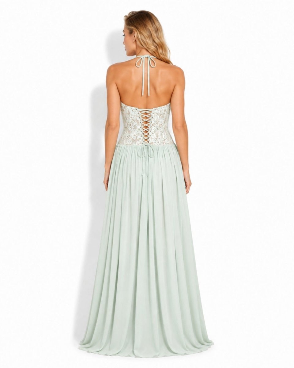 A woman modeling a mint green halter maxi dress from the back, featuring a lace-up corset-style bodice and a flowing chiffon skirt, set against a plain white studio background.