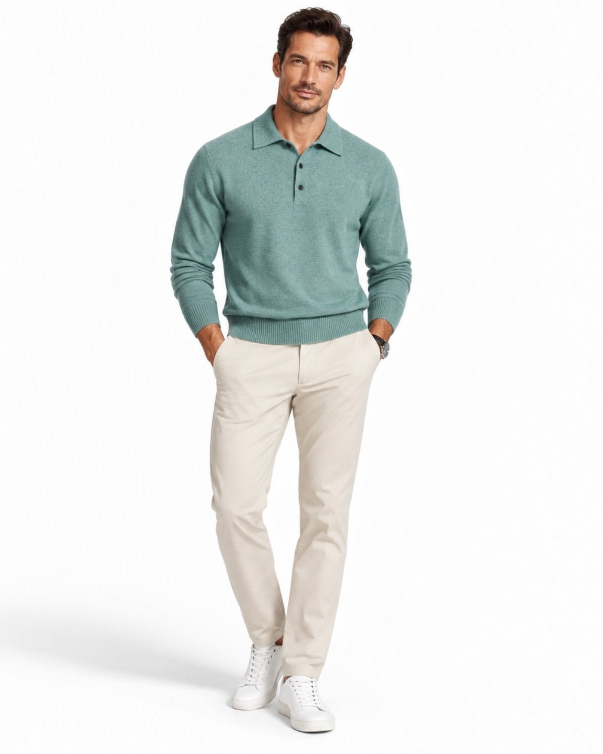 A man modeling a sage green long-sleeve knit polo shirt with beige trousers and white sneakers, standing against a plain white studio background.