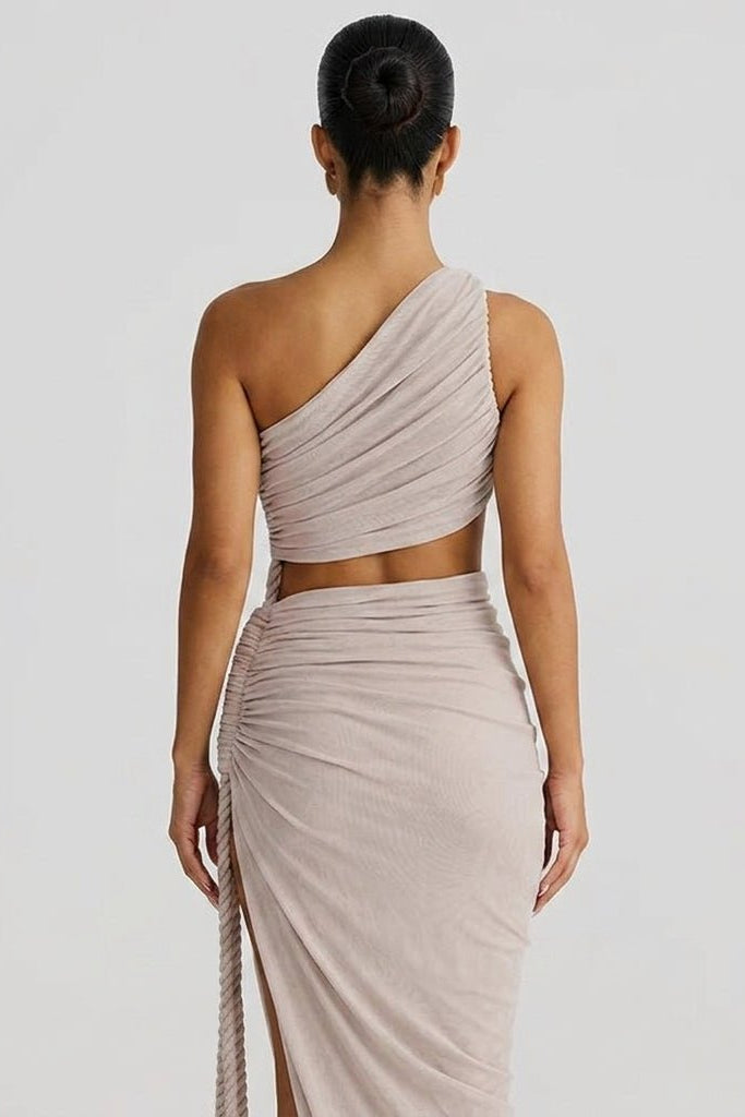 Back view of woman wearing an asymmetrical taupe draped maxi gown showing midriff cutout.