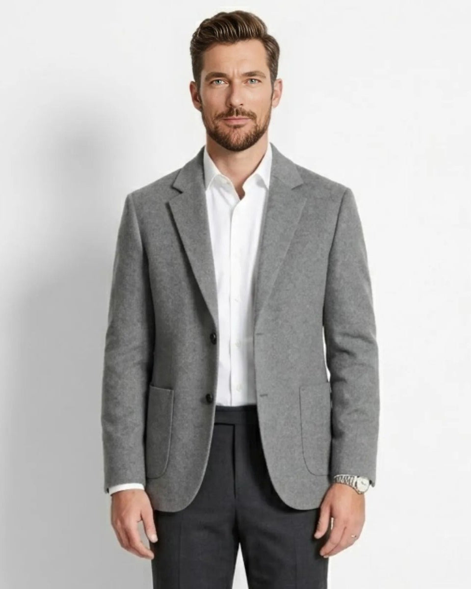 Man wearing a gray blazer over a white shirt on a light gray background