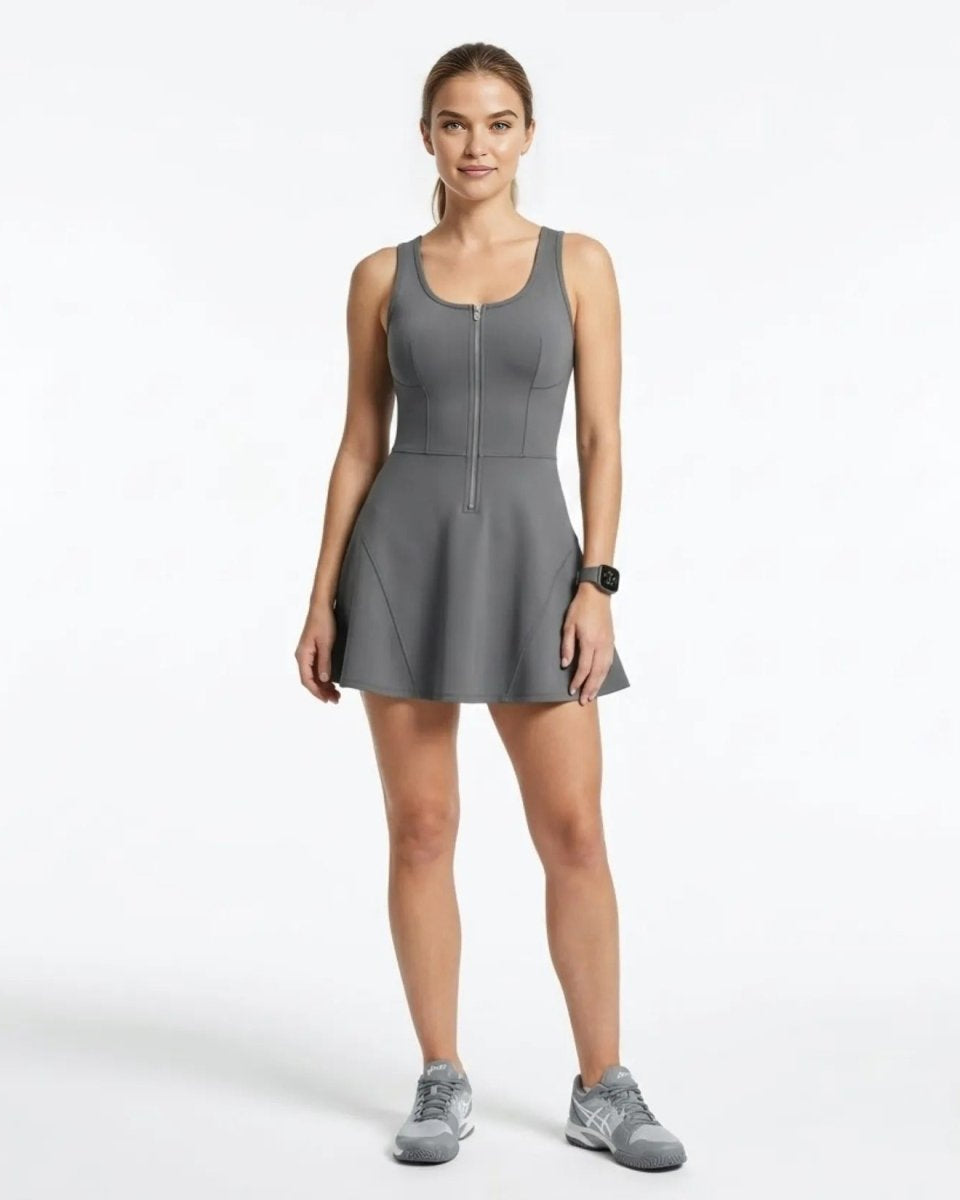 Woman wearing a grey zip-front sleeveless tennis dress with flared skirt by Kouvr