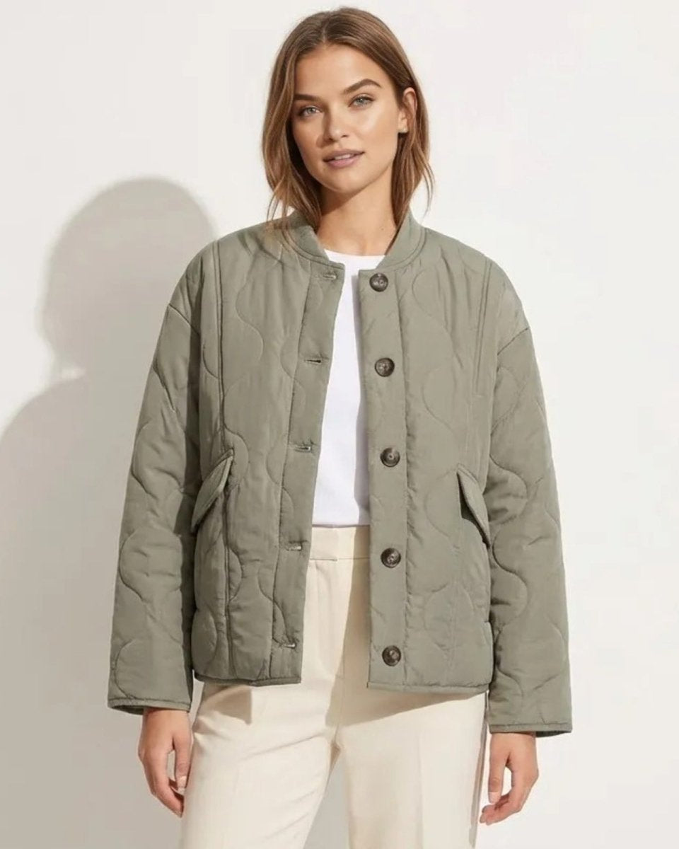 Model wearing the Harmony sage green quilted liner jacket, buttoned over a white t-shirt and cream trousers, showing its relaxed, oversized fit.
