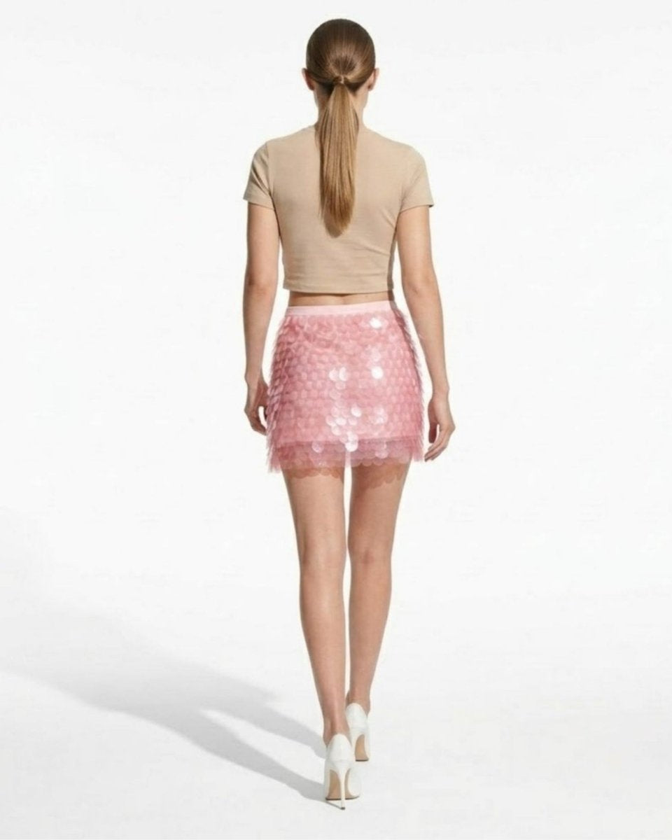 Back view of a high-waisted pink sequin skirt showing the layered disc texture, banded waist, and flattering mini length.