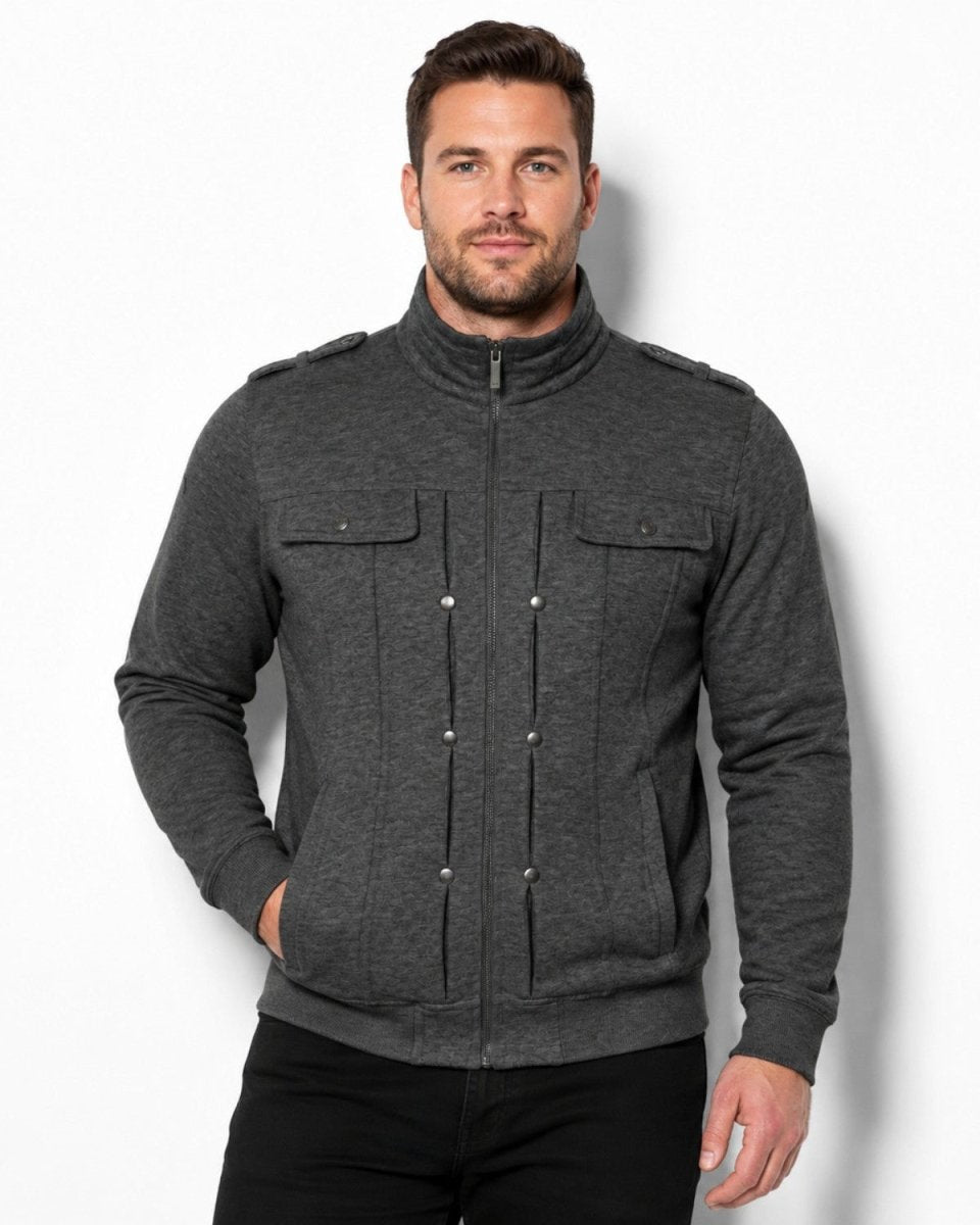 A man wearing a dark gray heather zip-up jacket with a mock neck, buttoned front placket, and flap chest pockets, paired with black pants, against a plain white studio background.
