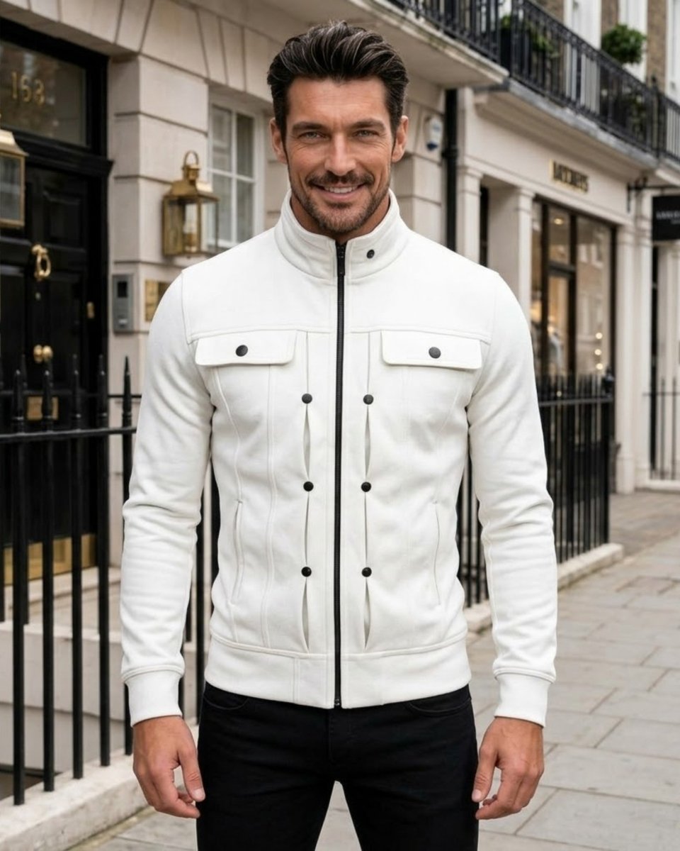 A man wearing a white leather jacket with black buttons and a stand-up collar, standing on a city street in front of a building.