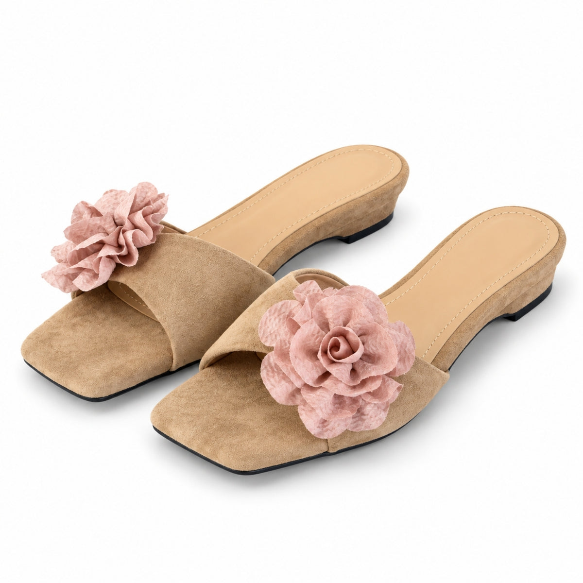 A pair of khaki suede slide sandals with a large pink fabric flower embellishment on the toe strap, shown against a plain white background.