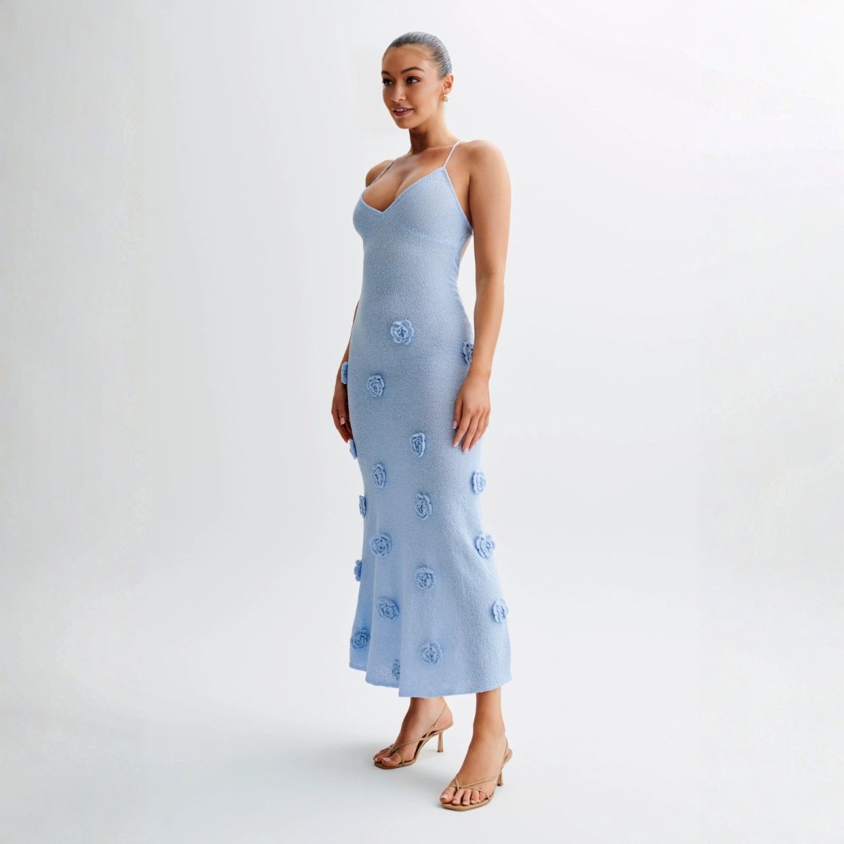 Woman wearing a light blue dress with floral patterns on a white background