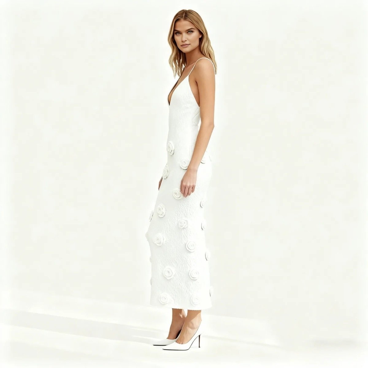 Woman wearing a white kouvr dress with floral details on a white background