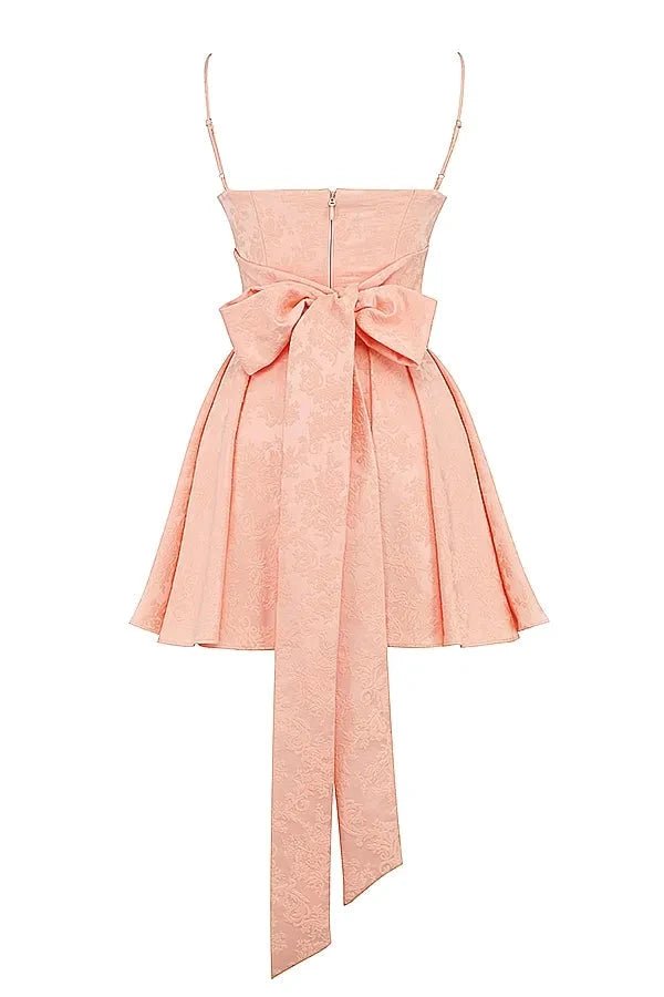Model wearing Kouvr Ayliah peach jacquard mini dress with large bow detail at the back