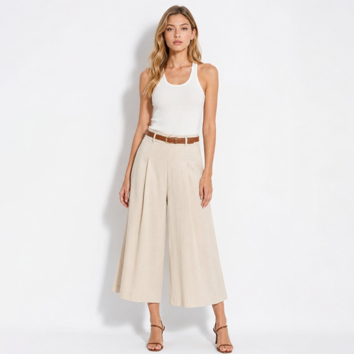 Styled front view of Kouvr light khaki pleated summer culottes paired with white ribbed tank top.