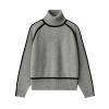 Flatlay of a gray turtleneck sweater with black piping detail, showing the ribbed hem and cuffs.