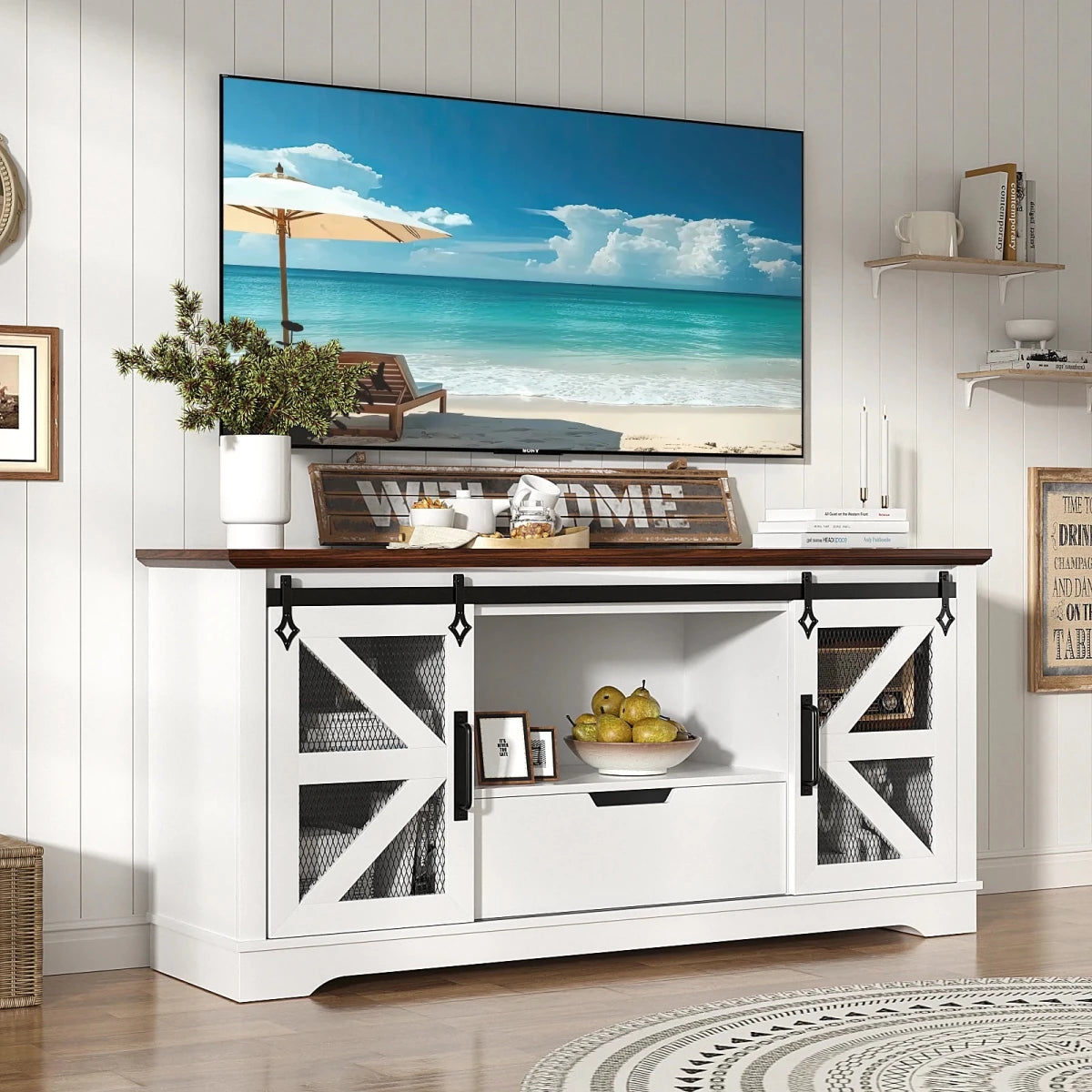 A 60-inch white and walnut farmhouse TV stand by Kouvr, featuring sliding barn doors with mesh, styled in a bright, modern living room with a large screen television.