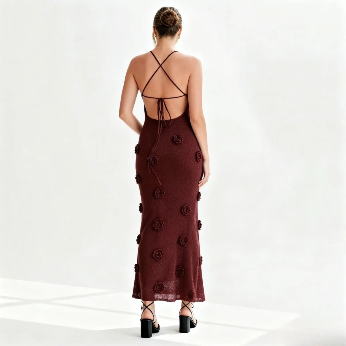 Woman wearing a burgundy evening gown with floral embellishments on a white background