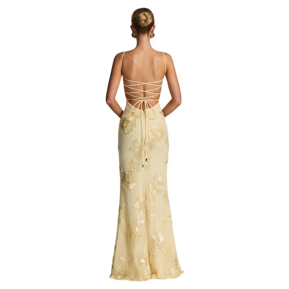 Woman wearing a yellow kouvr evening gown with floral embroidery on a white background