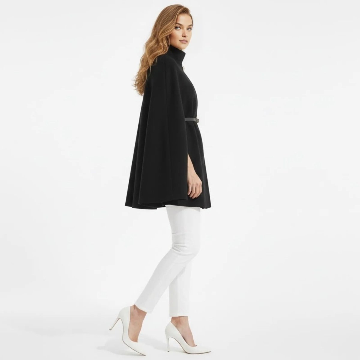 Side profile of a woman walking in the Kouvr Fashion black belted cape coat, showcasing the garment's A-line drape and structure.