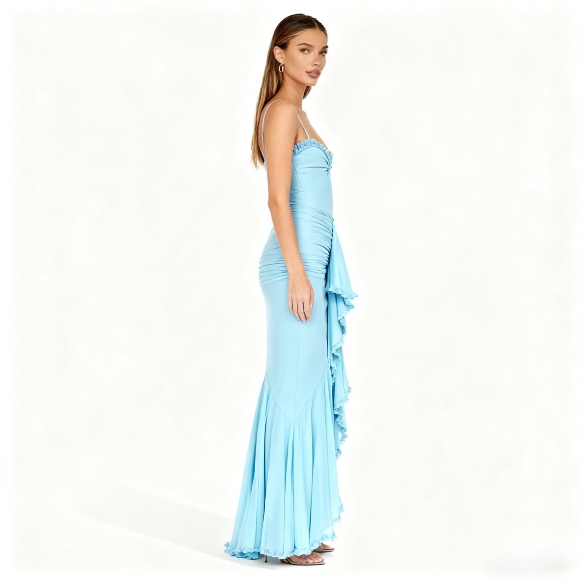 Woman wearing a light blue kouvr evening gown with ruffled details on a white background