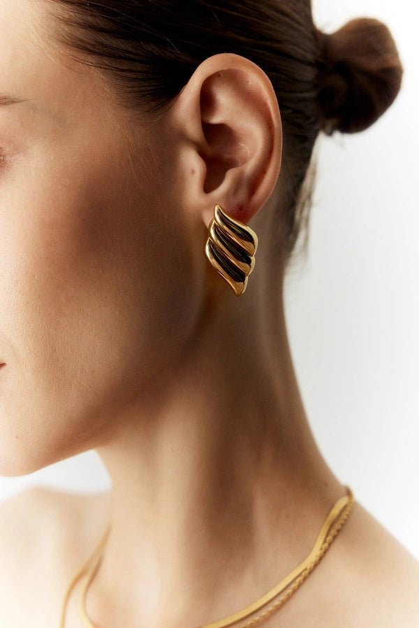 A detailed close-up shot of the Kouvr Fashion silver architectural statement earrings on a model's ear, highlighting the ribbed texture.
