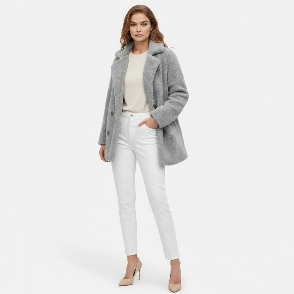 Model wearing the light grey double-breasted teddy coat from Kouvr Fashion with white jeans and nude heels, shown from the front.
