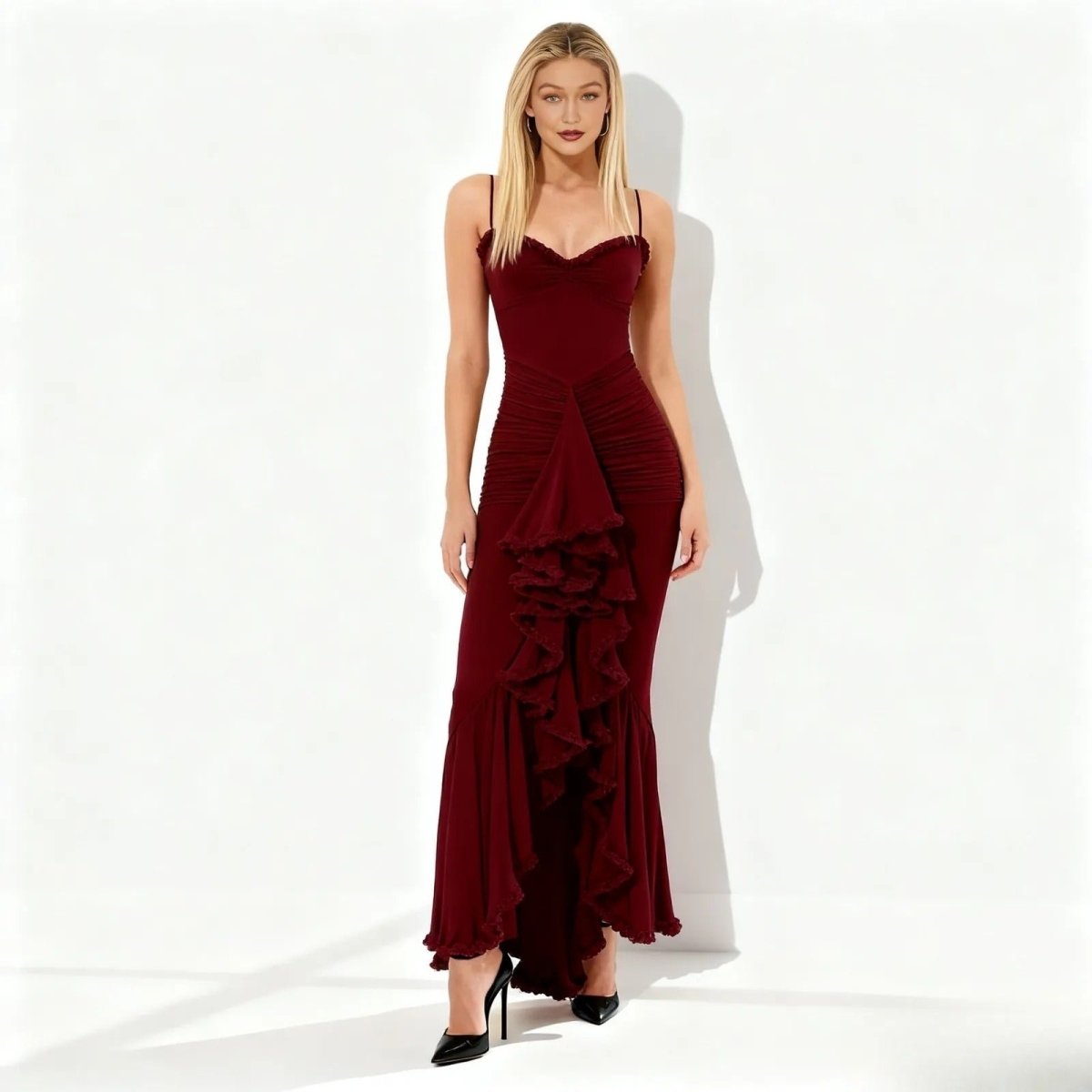 Woman wearing a maroon kouvr evening gown with ruffled details on a white background
