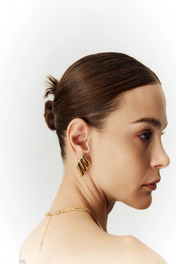 A detailed close-up shot of the Kouvr Fashion silver architectural statement earrings on a model's ear, highlighting the ribbed texture.