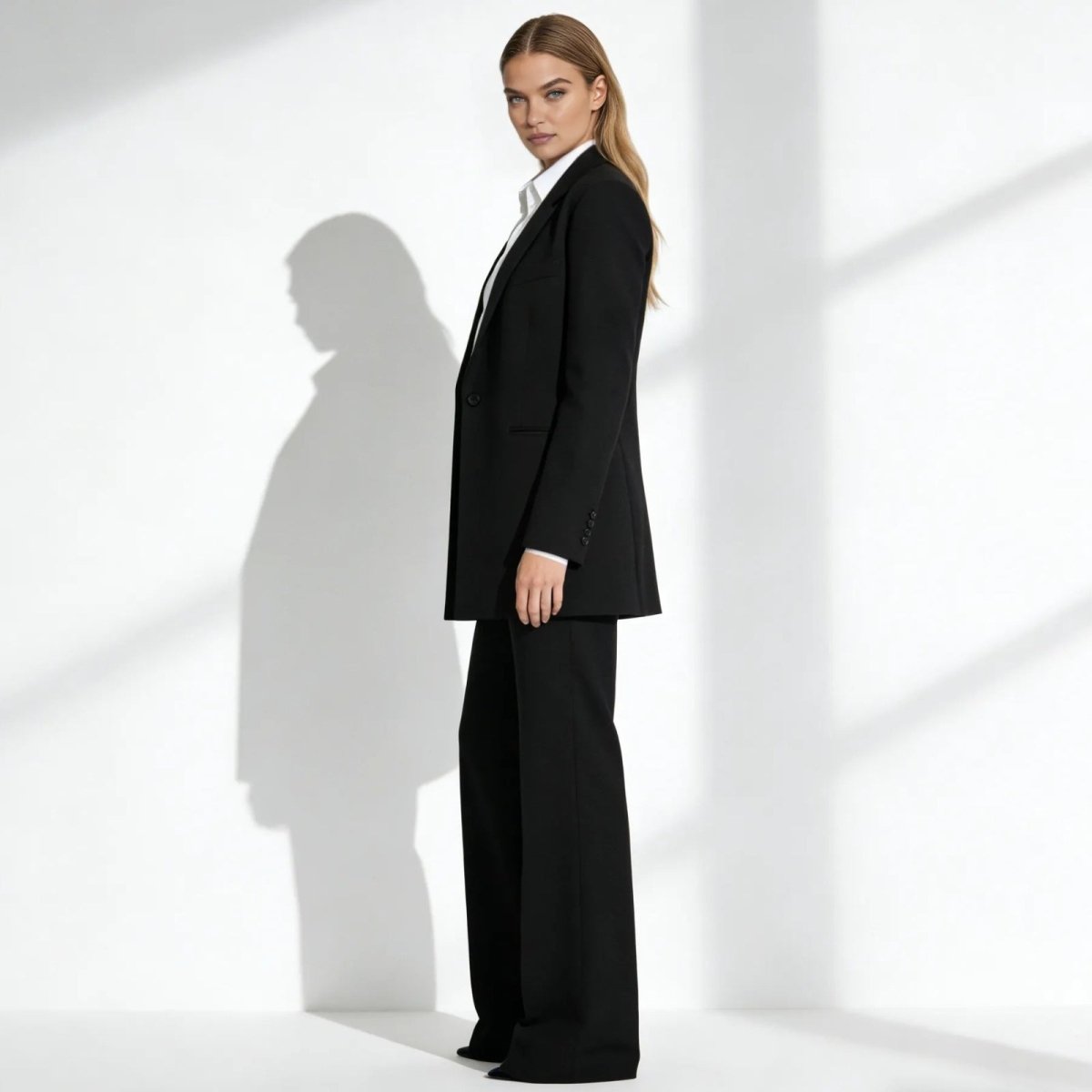 Side profile of a model in a black oversized blazer and flowing wide-leg pants from Kouvr Fashion, showcasing the suit's modern silhouette.
