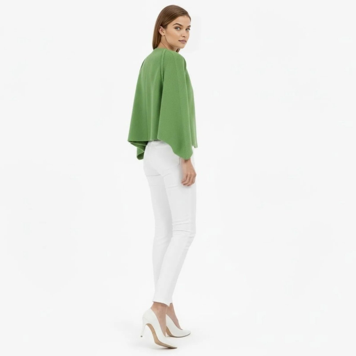 Model looking over her shoulder showing the back view of the Kouvr Laverne green wool-blend cape jacket.
