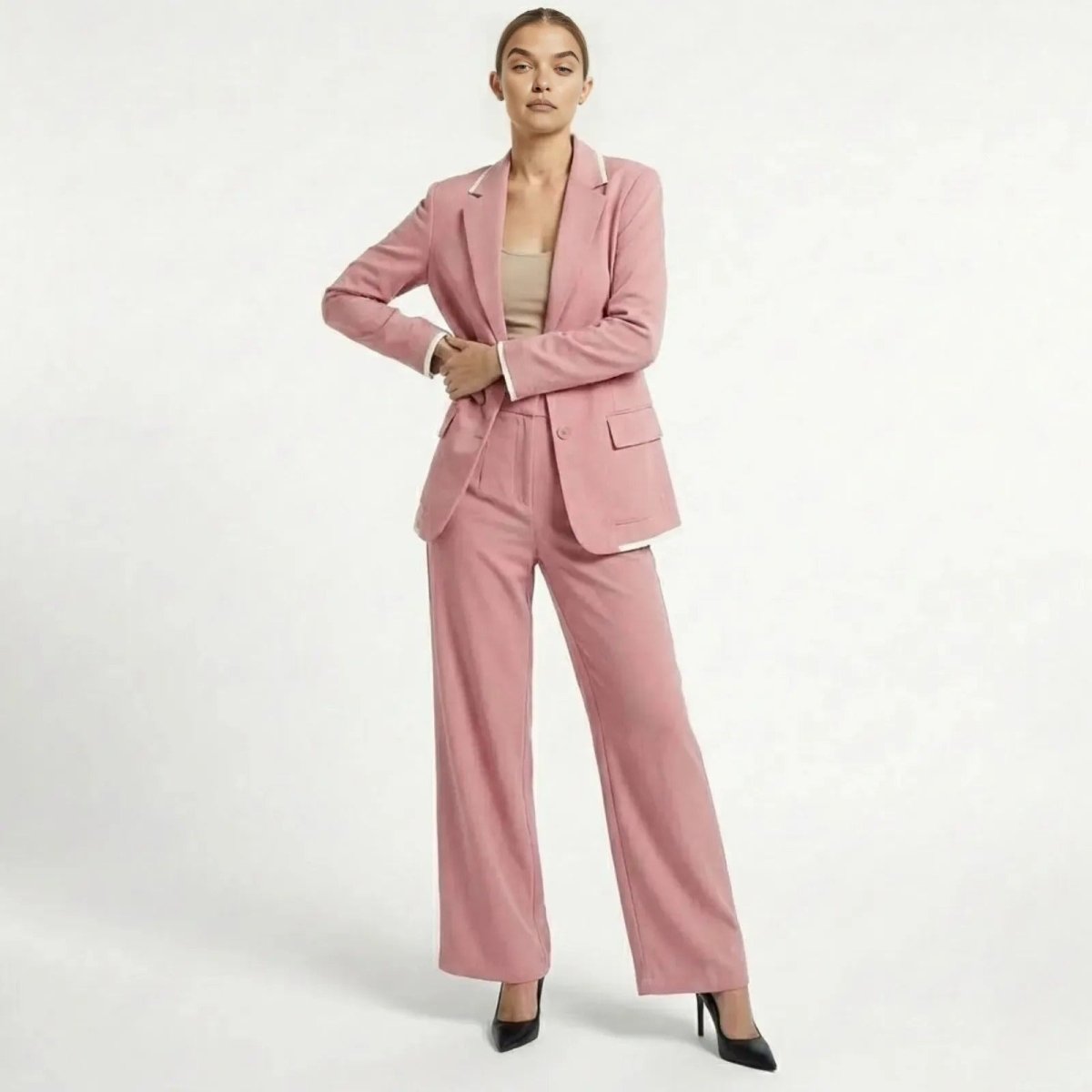 A female model wearing the Kouvr Lucia Set women's pink pantsuit with wide-leg trousers and a single-breasted blazer, posing confidently against a white background.