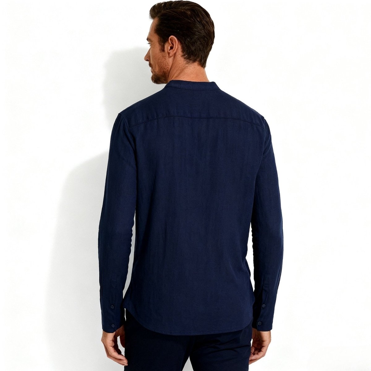 Back view of a man in the Kouvr navy linen grandad collar shirt, highlighting the shoulder yoke and construction.