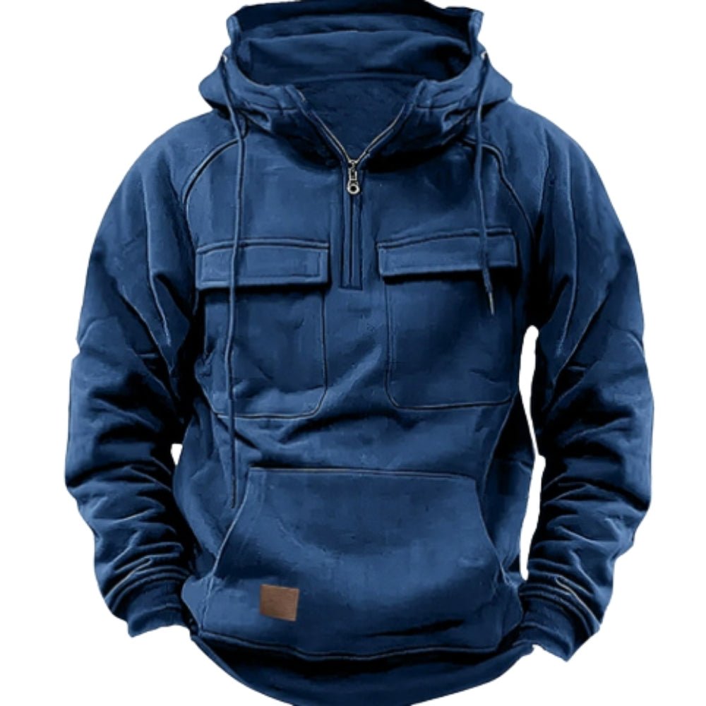 Close-up detail shot of the Kouvr Dominic hoodie's slate blue fabric, metal half-zip, and utility chest pocket.