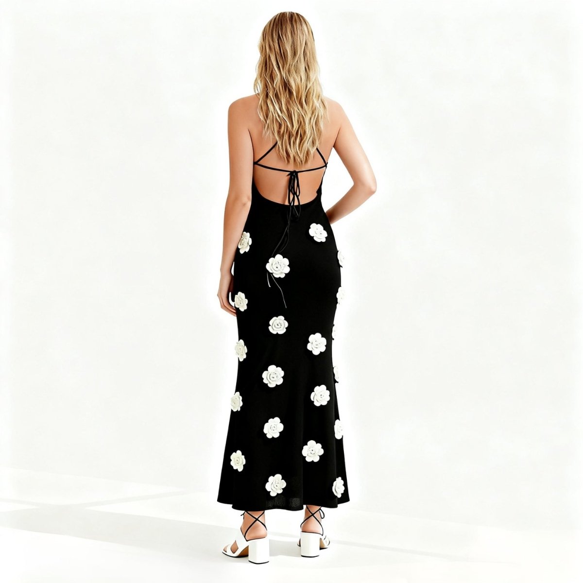 Woman wearing a black kouvr dress with white floral patterns on a white background