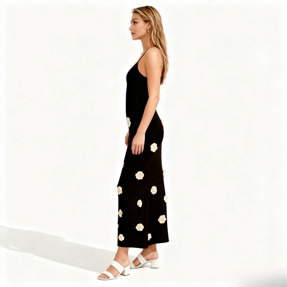 Woman wearing a black kouvr dress with white floral patterns on a white background