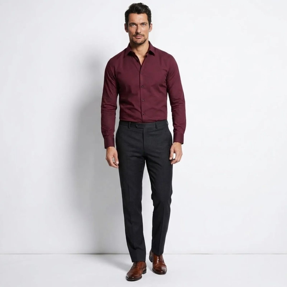 Man wearing The Leland slim fit long sleeve dress shirt in burgundy by Kouvr, paired with charcoal trousers.