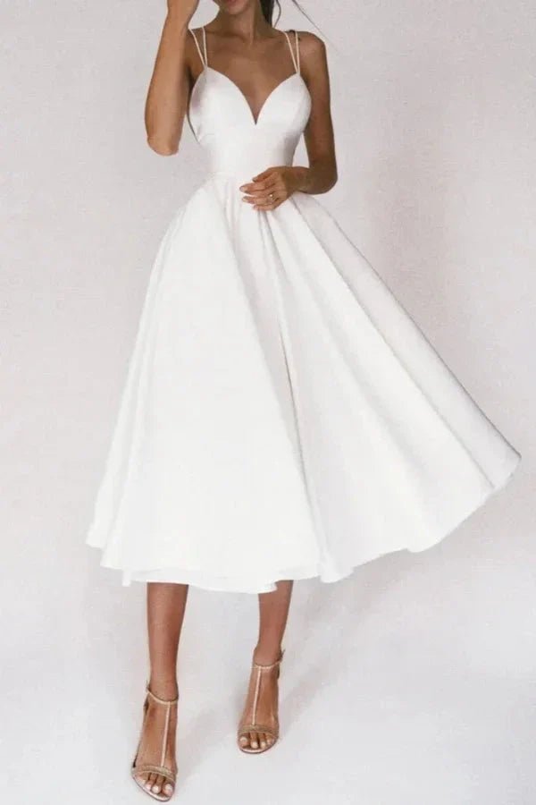 Model from behind wearing The Alazne white satin midi dress showing the criss-cross open back straps