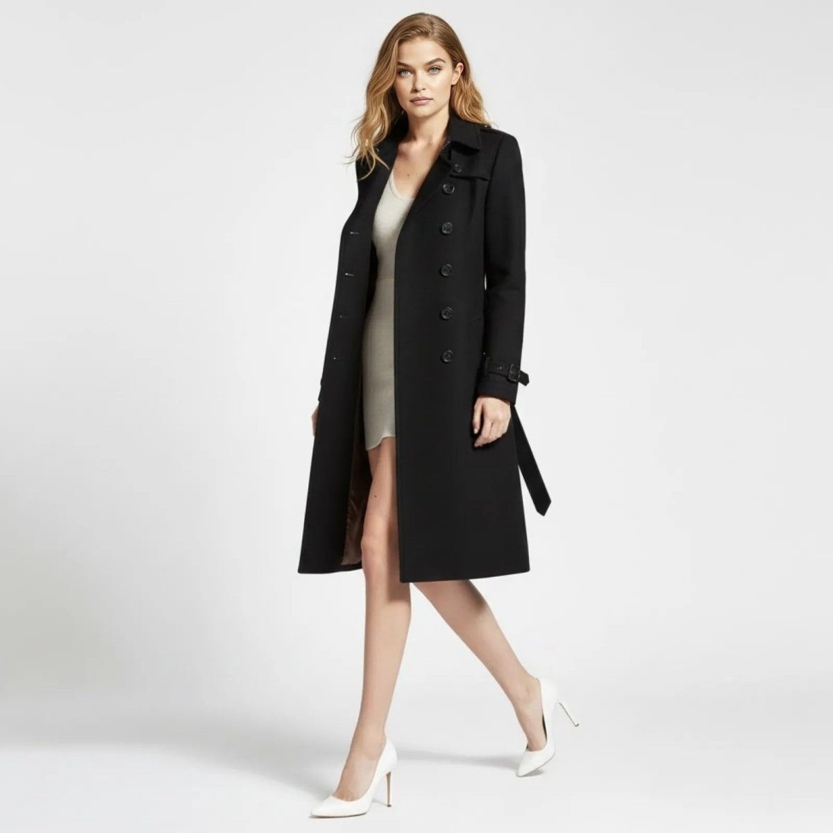 Side profile of a woman walking in a classic black knee-length wool trench coat by Kouvr, showing the coat's movement and silhouette.