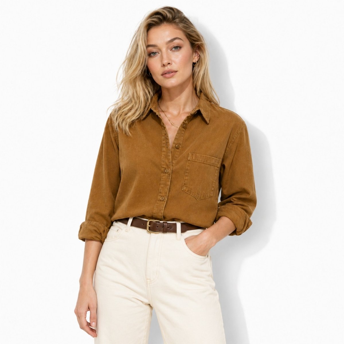 Woman styling the Kouvr brown long sleeve corduroy top partially tucked into white denim with a brown leather belt
