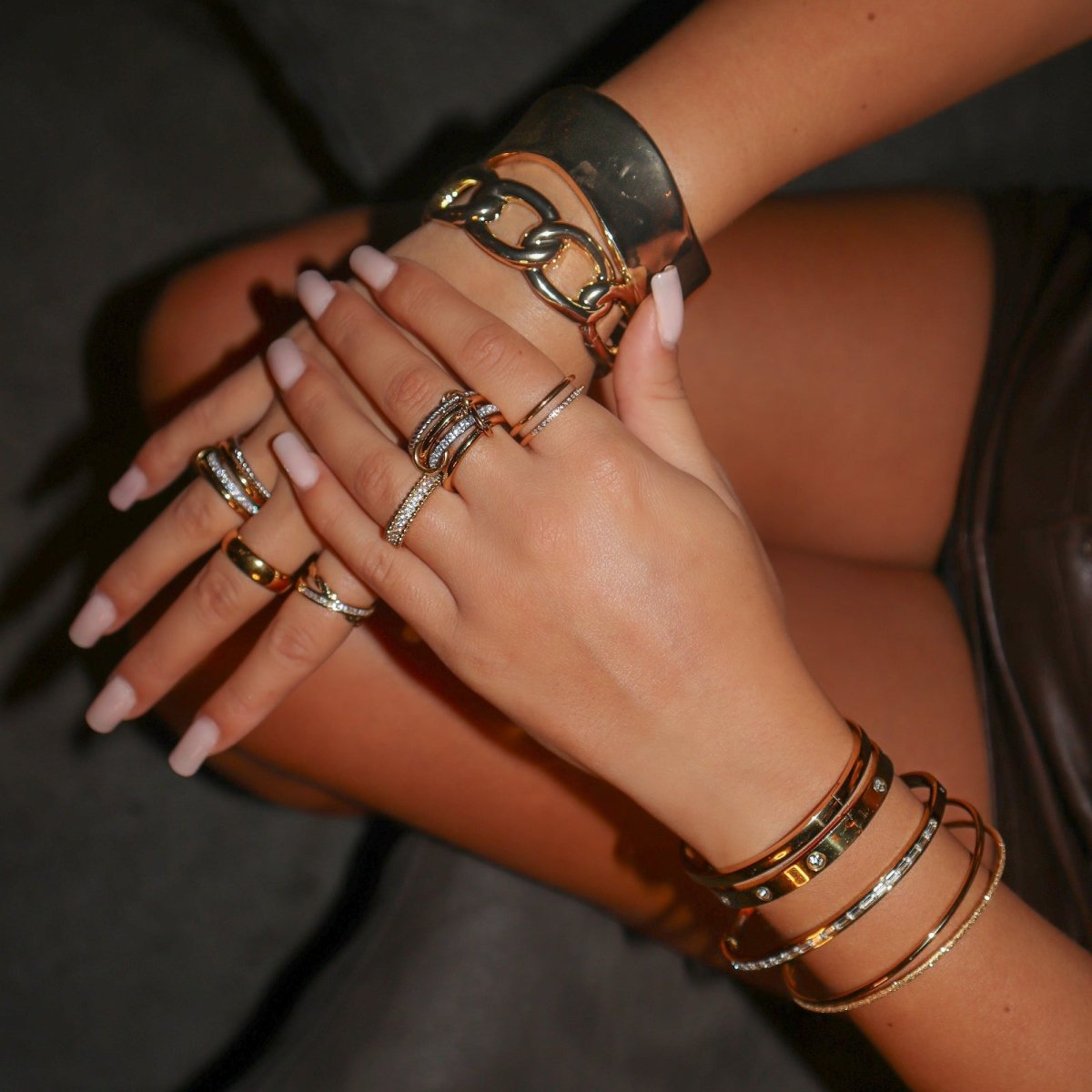 A lifestyle view of the Kouvr Zeina multi-band diamond ring stacked with gold bracelets on a model's hands.