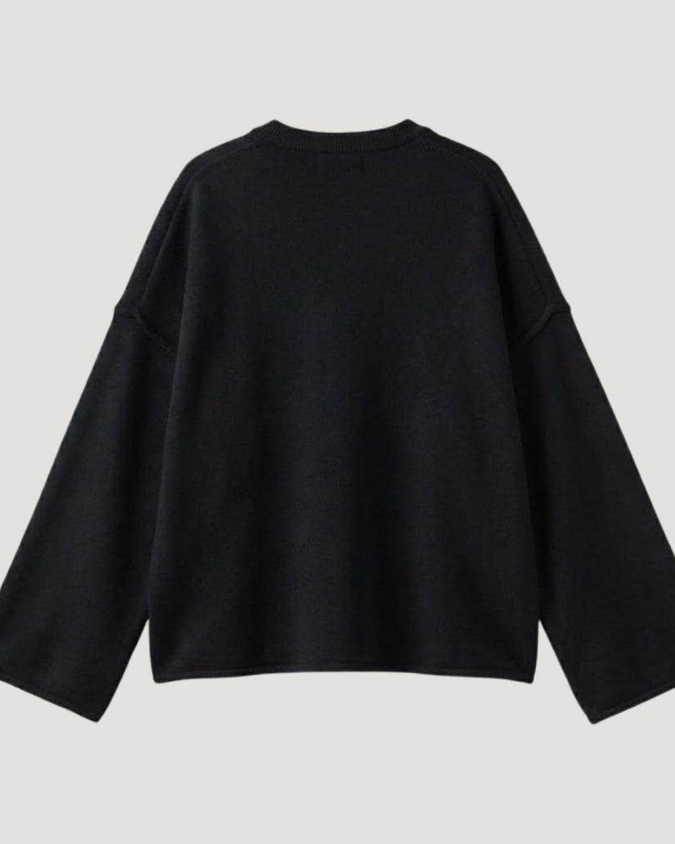 Back view of a black oversized knit pullover showing the texture of the fabric and the minimalist design for women's luxury fashion.