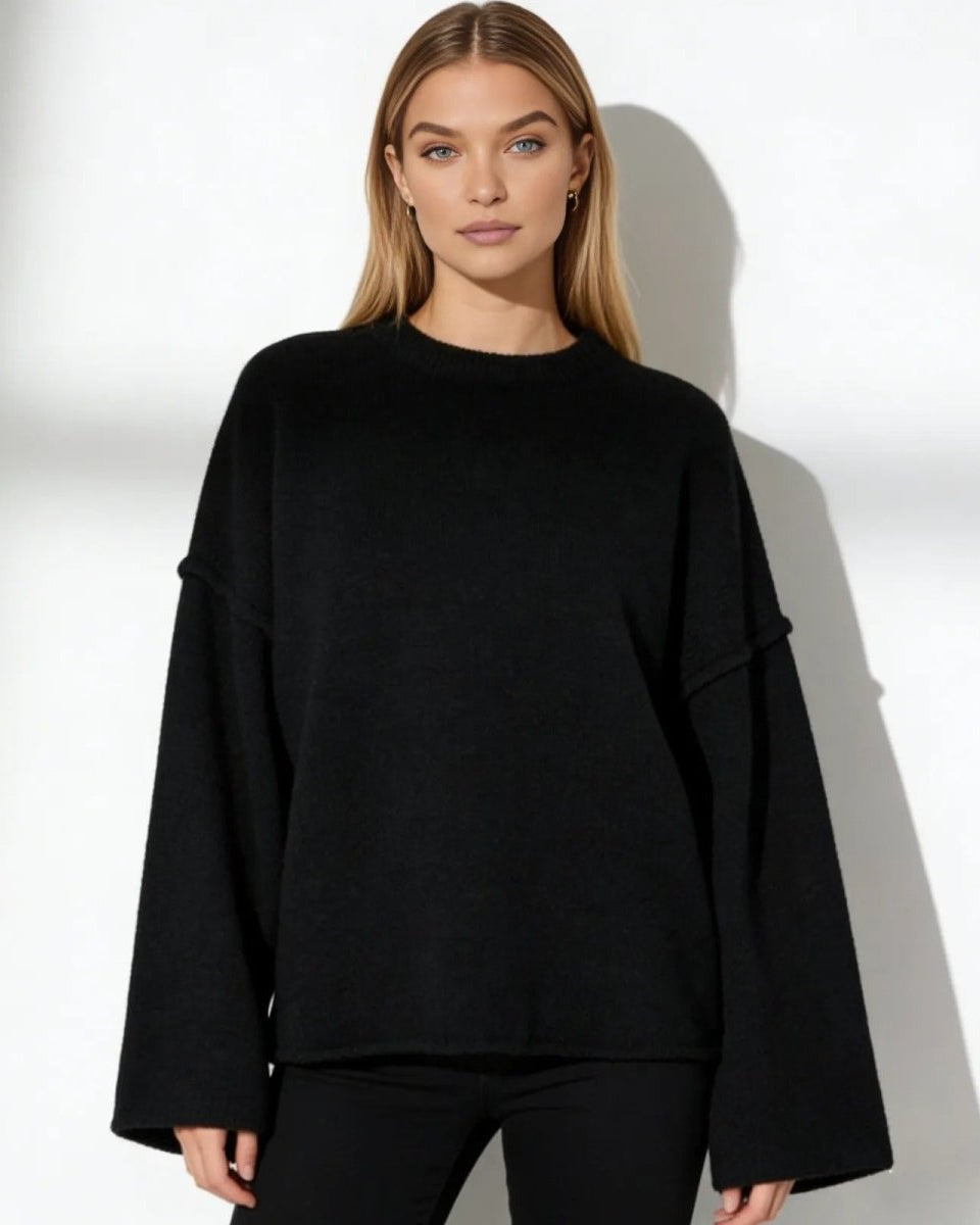 Model wearing the Krystal oversized black sweater with wide bell sleeves, showcasing its slouchy, minimalist fit.