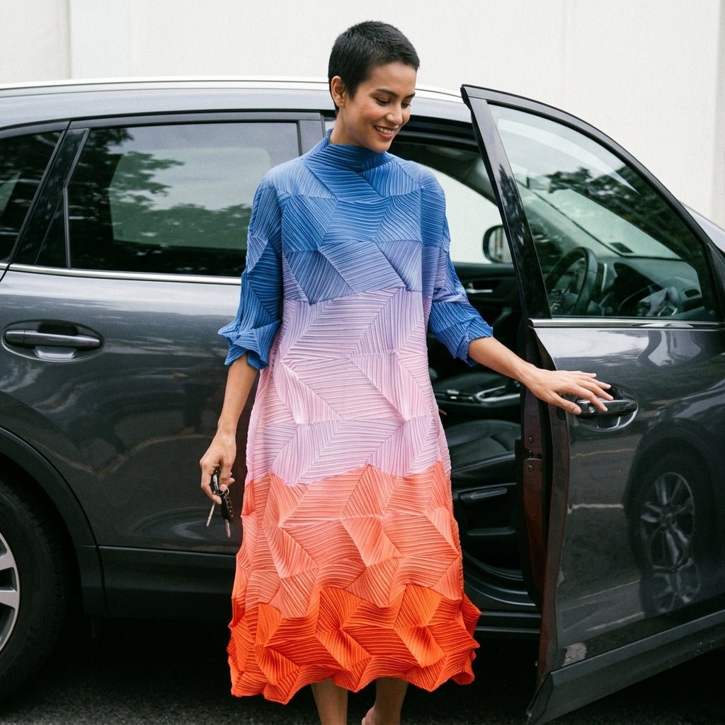 Smiling elegant woman wearing the Kouvr sunset ombre pleated midi dress stepping out of a luxury car.
