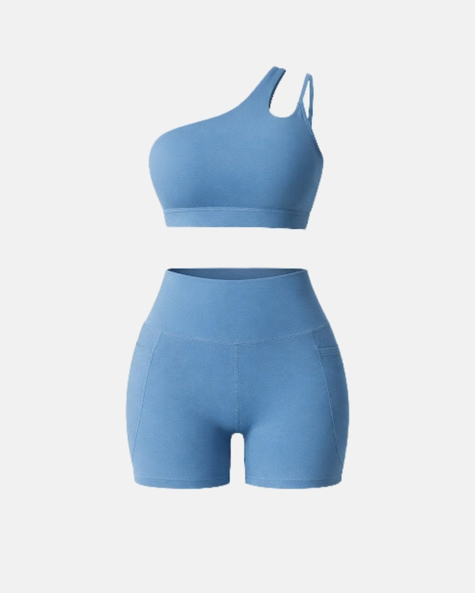 Front view of luxury light blue matching workout set featuring one-shoulder crop top and pocket biker shorts against a clean white background.