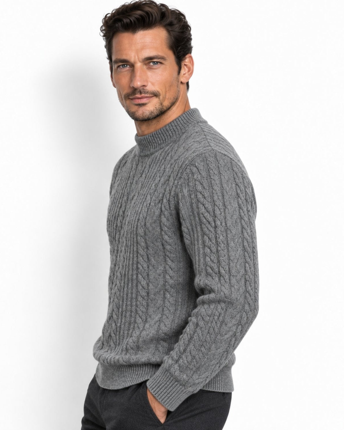 A man wearing a gray cable-knit mock neck sweater, shown from a three-quarters angle against a plain white studio background.